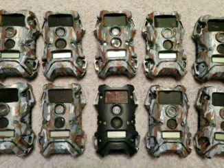 This photo shows 10 trail cameras — nine the author painted himself and one unpainted.