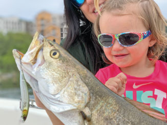 Charleigh Champagne, the 2 1/2-year-old daughter of Matrix Shad owner Chas Champagne, admires a huge speckled trout that fell for a Matrix Rip Shad.