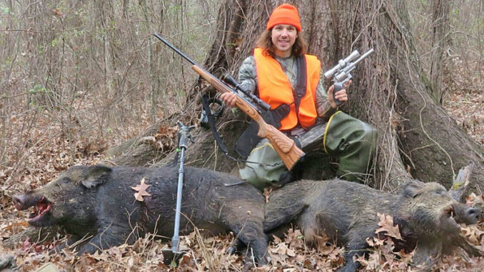 The author took these two hogs hunting near the base of the mature Nuttall oak tree he's leaning on.