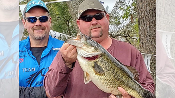 Jason Fails holds his nearly 12 pound win-win-win lunker largemouth as partner and net man David Gordon looks on.