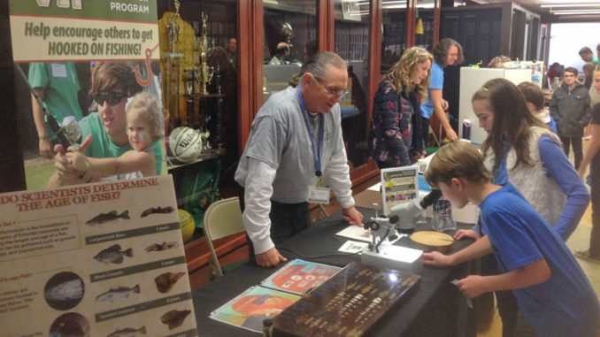 A volunteer instructor teaching about the growth of fish and how scientists determine their age just from a tiny ear bone.