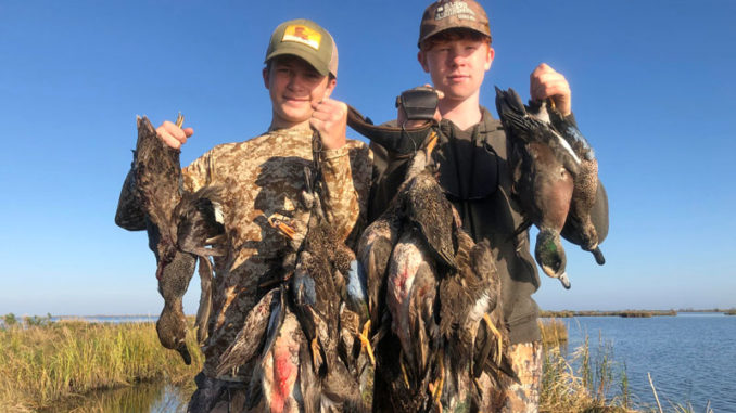 Jacob and Christian Mire holding up a four-man limit of Delacroix ducks.
