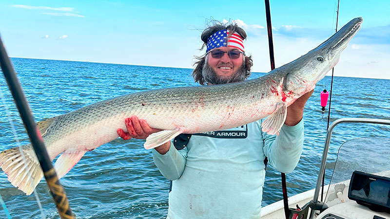 Chad Koch posing with a 6-foot alligator gar caught in Vermilion Parish on June 7.